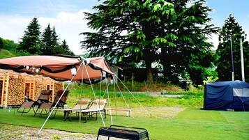 A campsite with a tent, a canopy, and a grill.