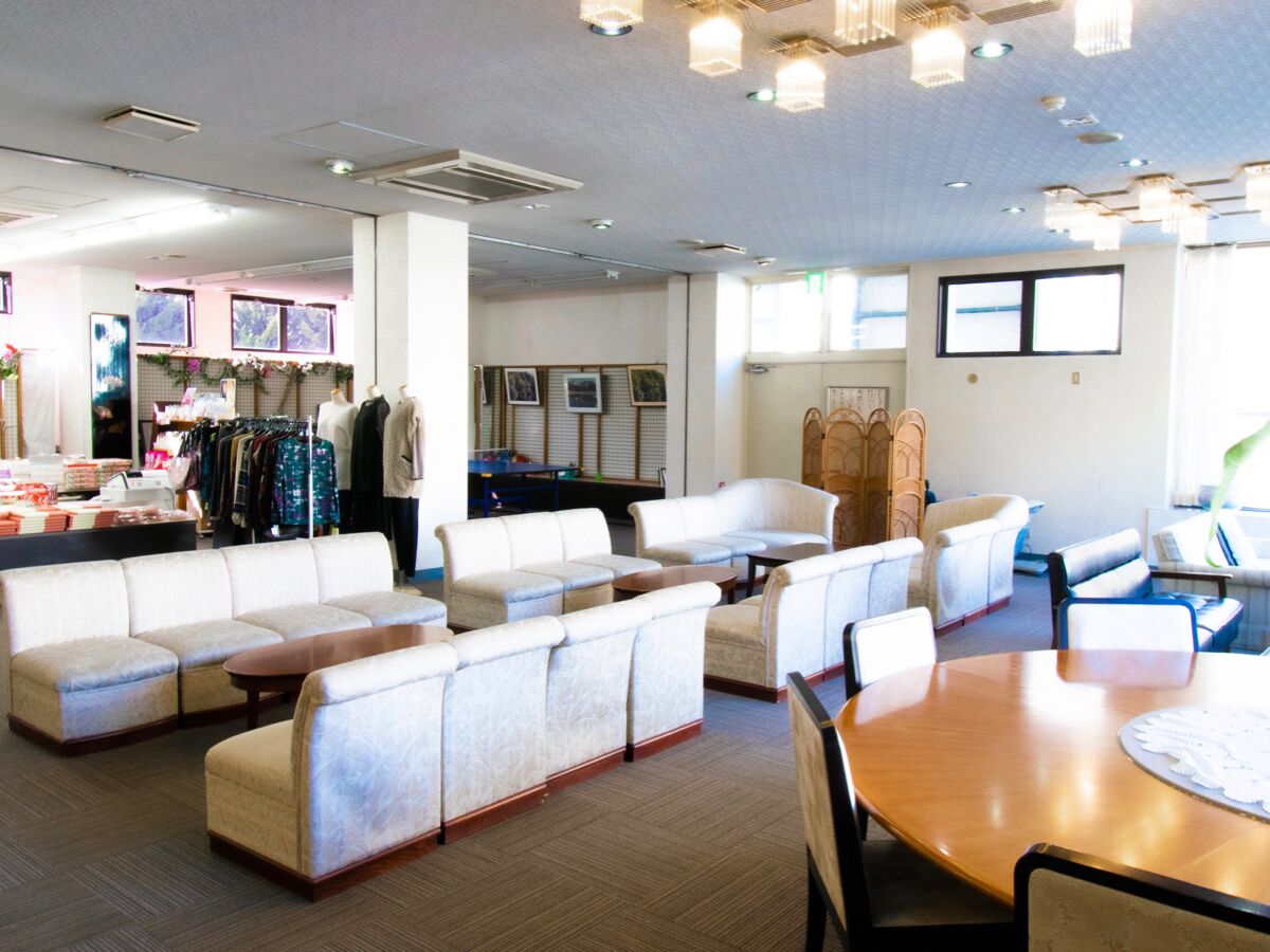 A hotel lobby with seating areas, a reception desk, and a clothing store.