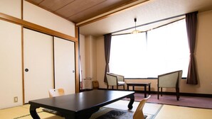 A traditional Japanese room with tatami flooring, a low table, two chairs, and a sliding door. - Ashinomaki Prince Hotel (Aizuwakamatsu)