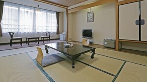 A traditional Japanese room with tatami flooring, a low table, a television, and a cabinet. - Ashinomaki Prince Hotel (Aizuwakamatsu)