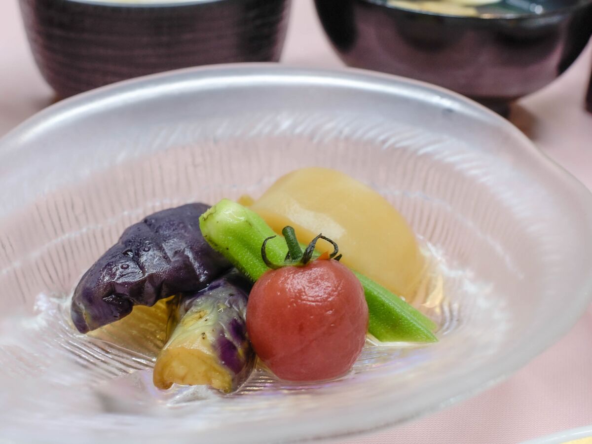 A clear glass bowl containing various fruits and vegetables.