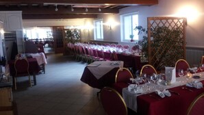 Un espace repas avec des tables dressées pour le service, comprenant une grande table avec des chaises et une table plus petite recouverte d’une nappe blanche.