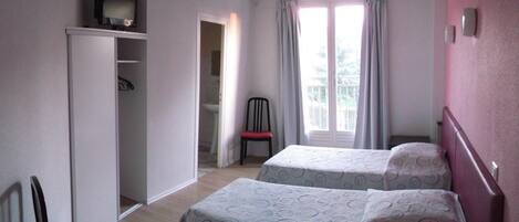 Un dormitorio con dos camas, un armario, una silla y una ventana con cortinas.