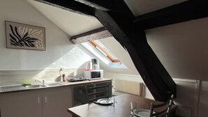 Une petite cuisine accueillante, avec une table à manger, une fenêtre donnant sur un beau paysage et un radiateur.
