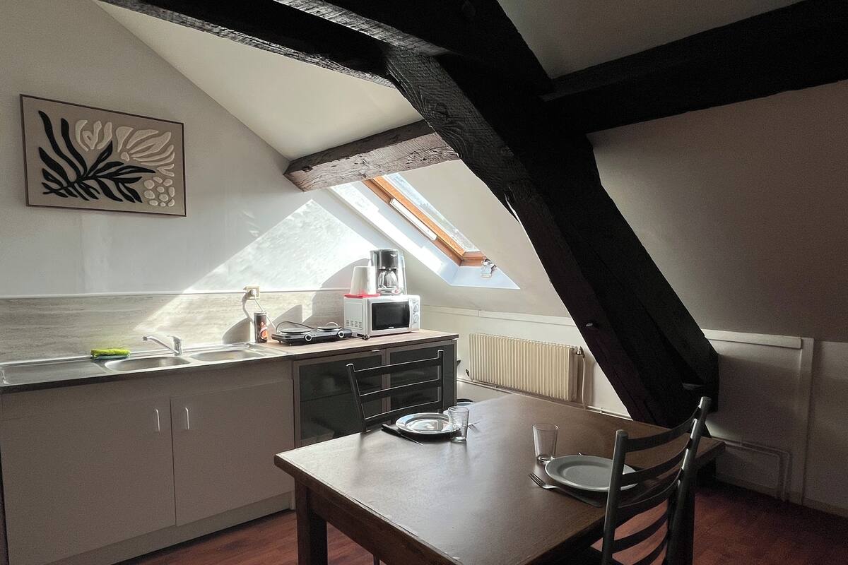 Une petite cuisine accueillante, avec une table à manger, une fenêtre donnant sur un beau paysage et un radiateur.