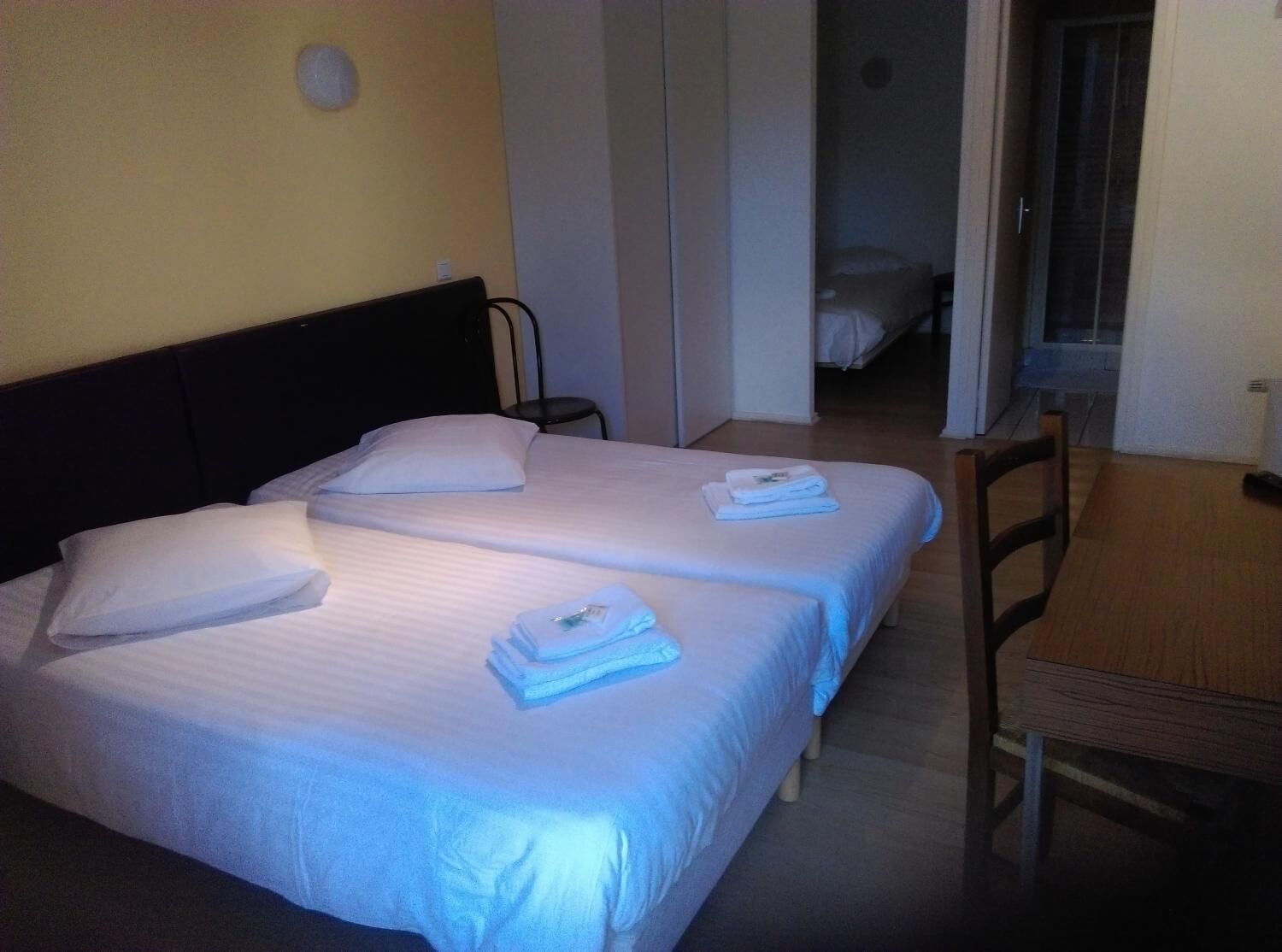 Une chambre d’hôtel avec deux lits, une chaise en bois et une petite table.