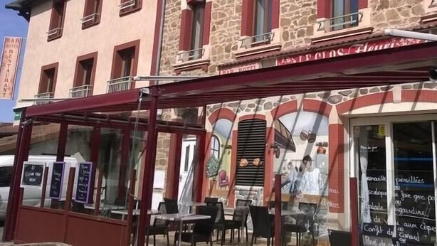 Un restaurant doté d’une terrasse, d’une façade en pierre et d’une enseigne indiquant qu’il s’agit d’un restaurant.