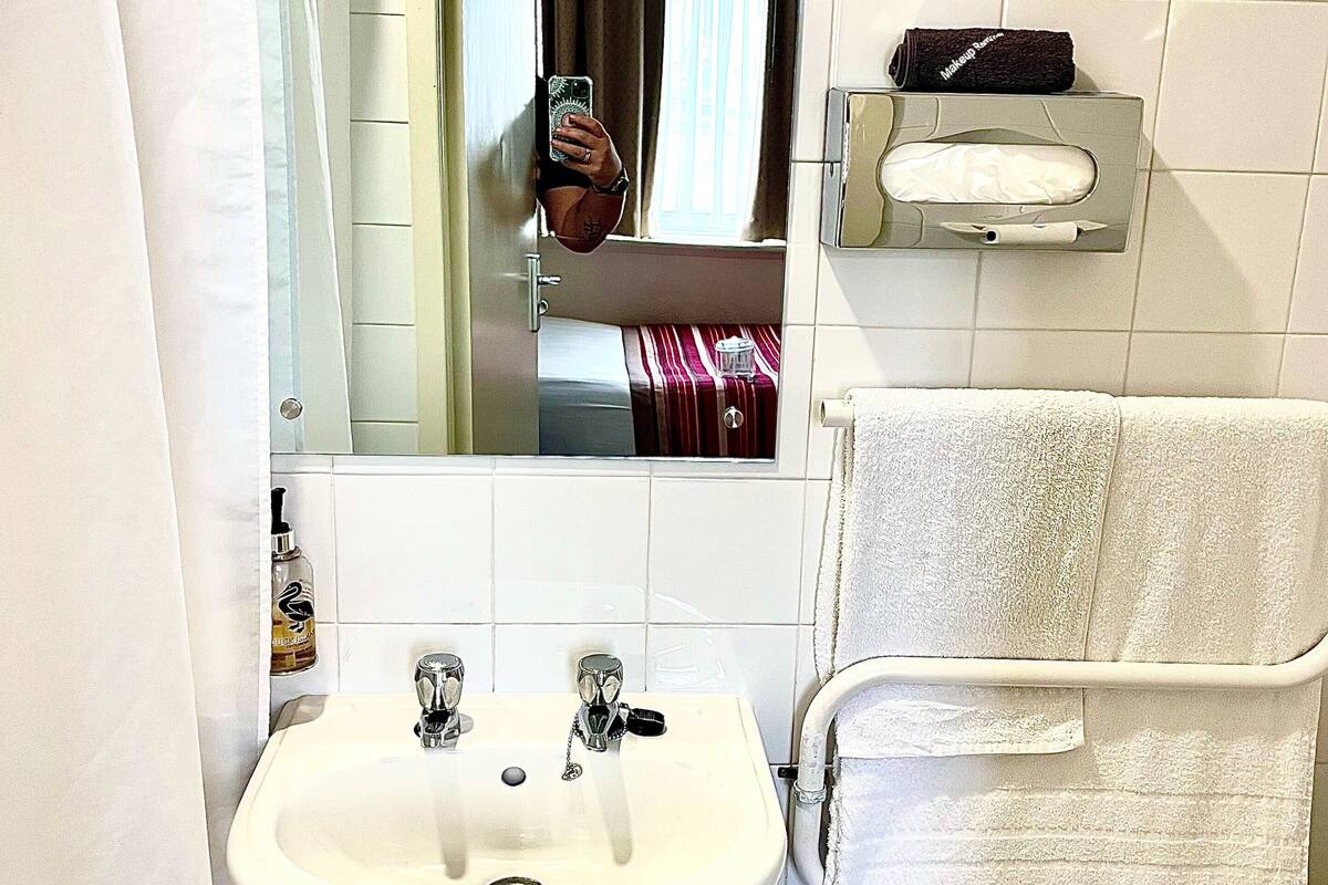 A bathroom with a white sink, a mirror, and a towel rack.