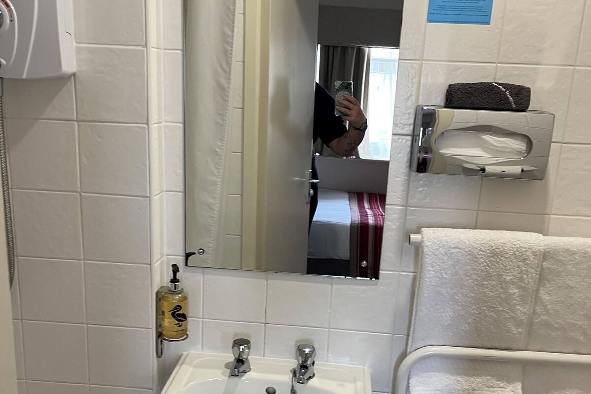 A bathroom with a white sink, a mirror, a towel rack, and a hand dryer.