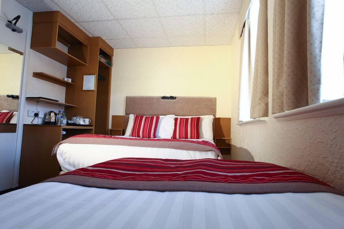 A hotel room with a bed, a wardrobe, a desk, and a window.