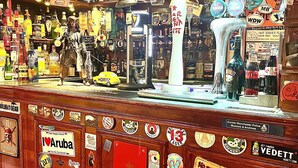 Un bar con mostrador de madera, diferentes botellas de licor y una grifería de cerveza grande.