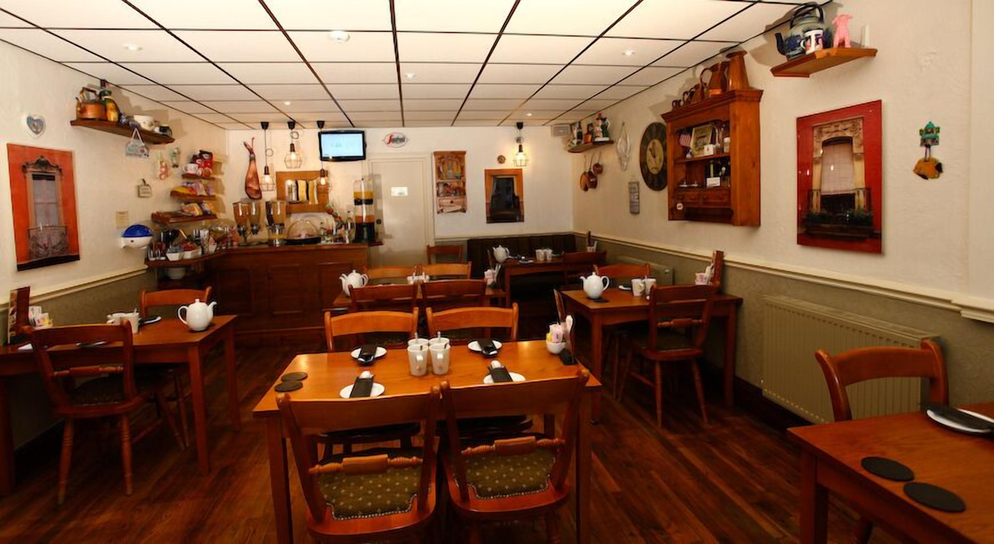 Un restaurante acogedor con mesas y sillas de madera, un televisor en la pared y diversas decoraciones.
