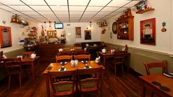 Un restaurante acogedor con mesas y sillas de madera, un televisor en la pared y diversas decoraciones.