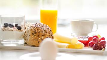 A breakfast setting with a glass of milk, a bowl of cereal with blueberries, a slice of bread, a glass of orange juice, a cup of coffee, and various fruits.