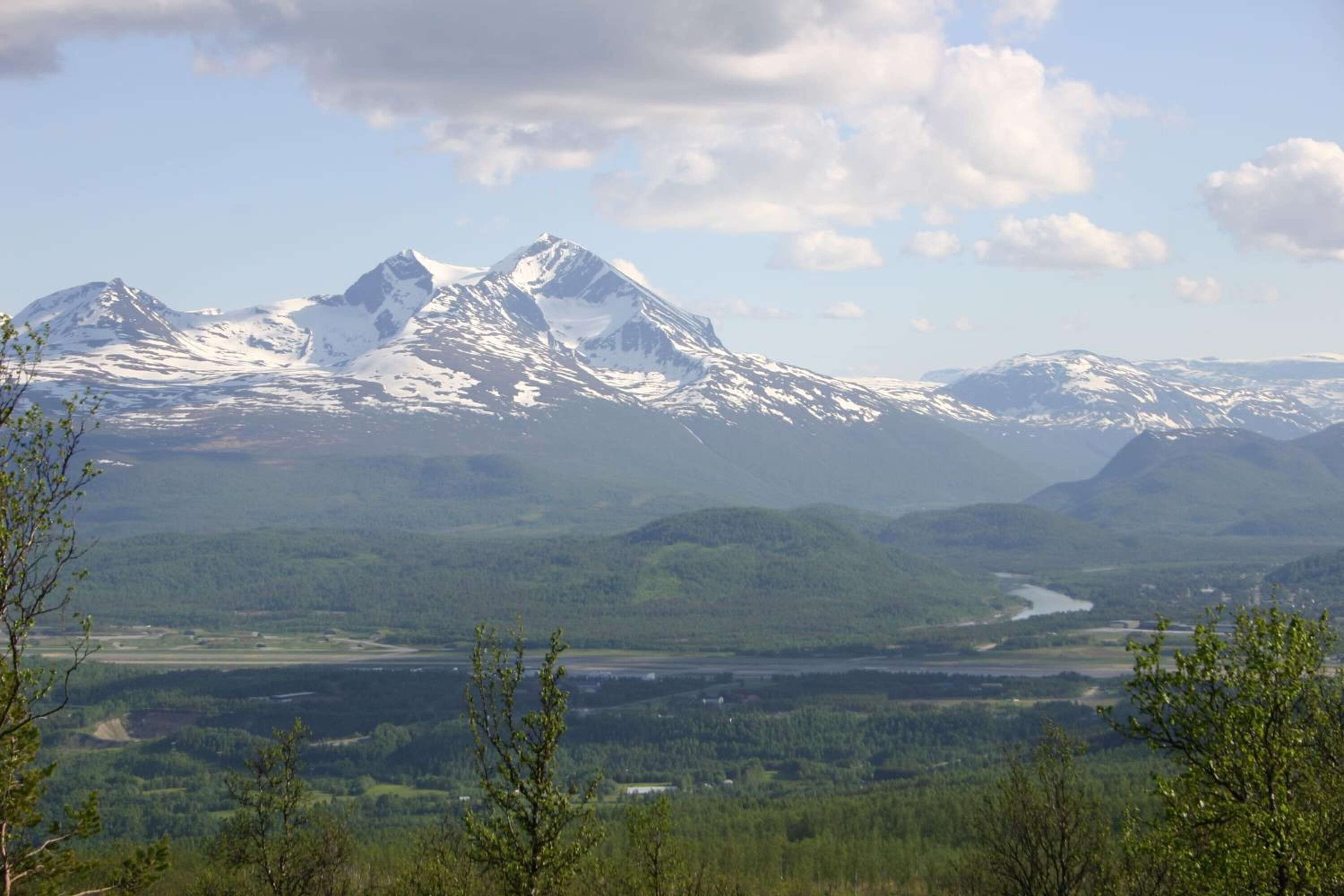 A mountain landscape with snow-capped peaks and a river valley below.