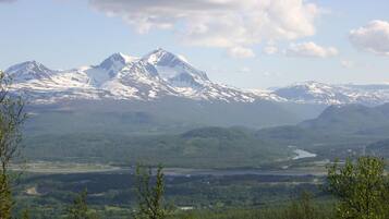 A mountain landscape with snow-capped peaks and a river valley below.