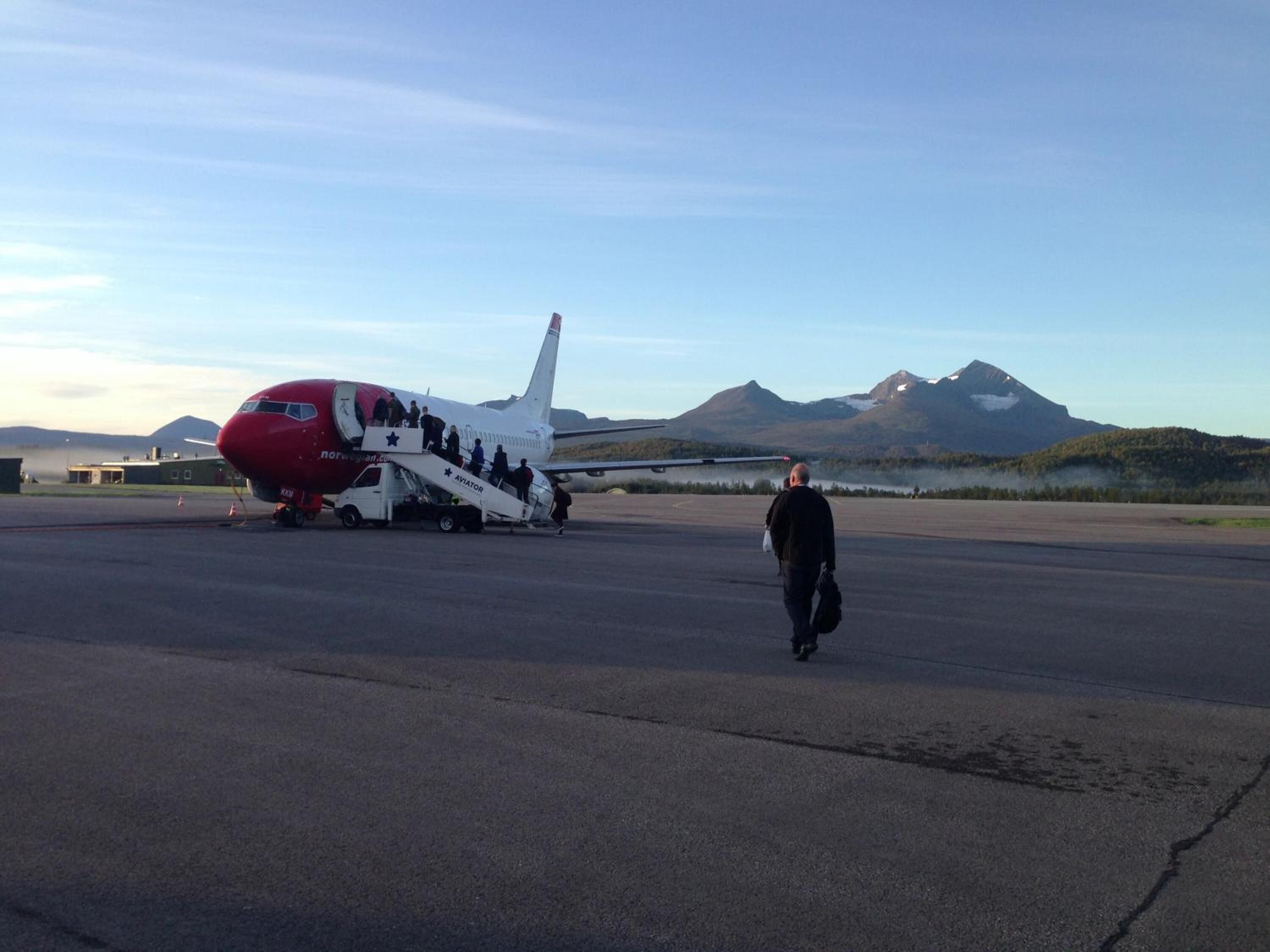 Un avion sur une piste d’atterrissage, avec une chaîne de montagnes en arrière-plan.