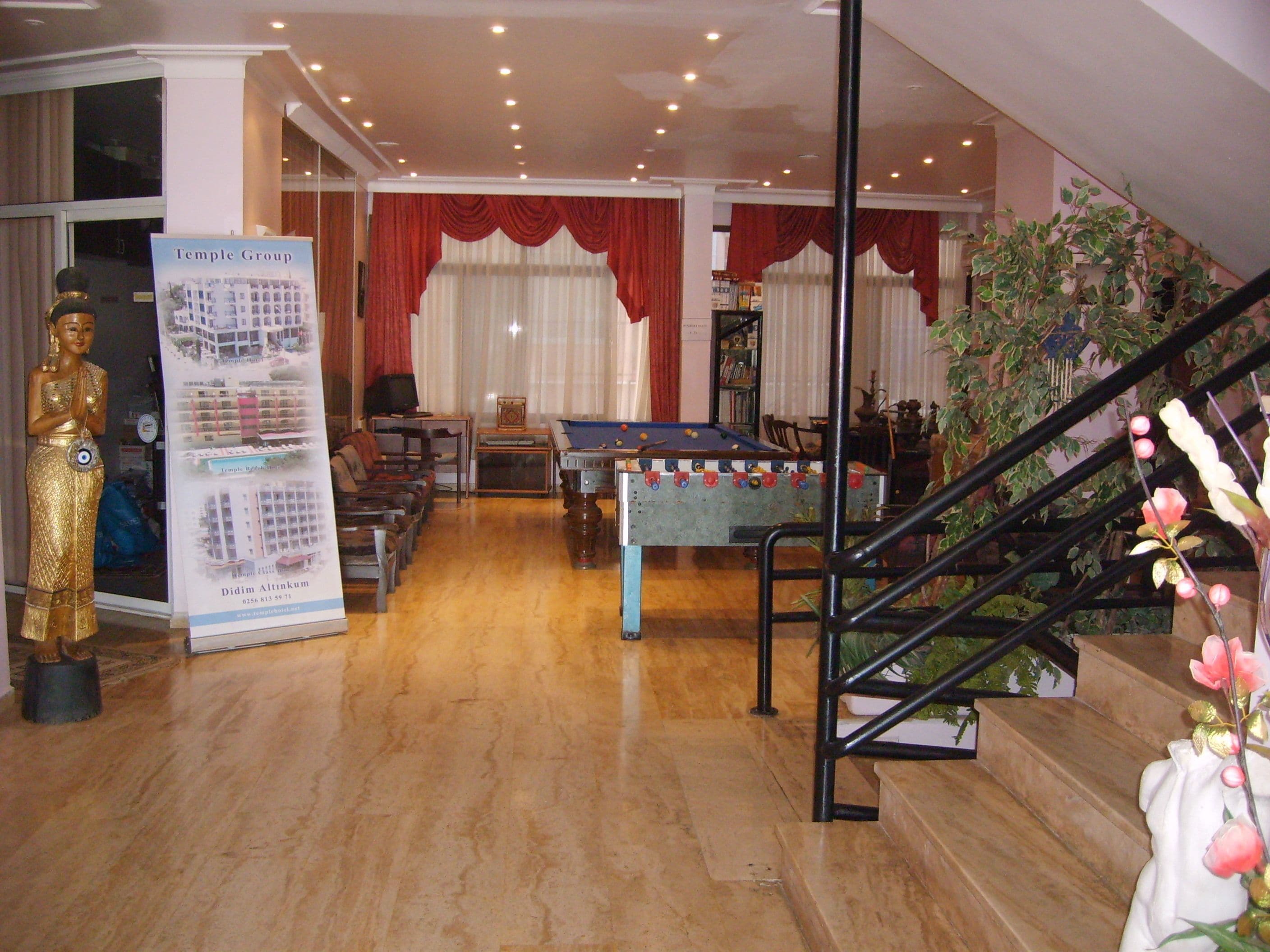 A lobby with a pool table, a Buddha statue, a staircase, and a signboard.