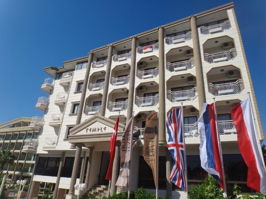 A multi-story hotel with balconies, flags, and a sign reading "Temple."