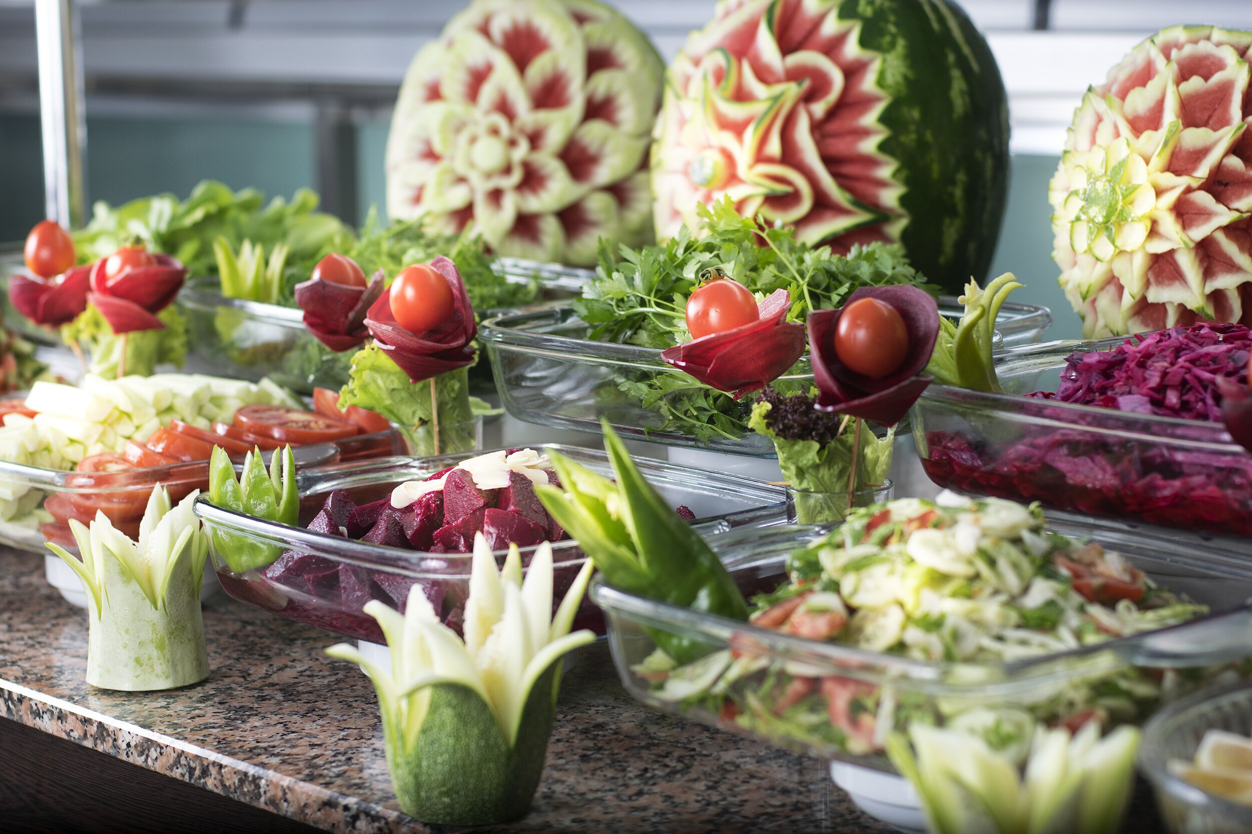 Un buffet proposant une variété de salades et des fruits sculptés.