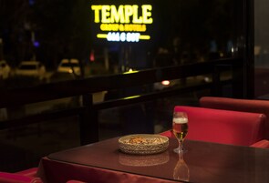 Un restaurante con un letrero de neón, una mesa con un cuenco de nueces y una jarra de cerveza.