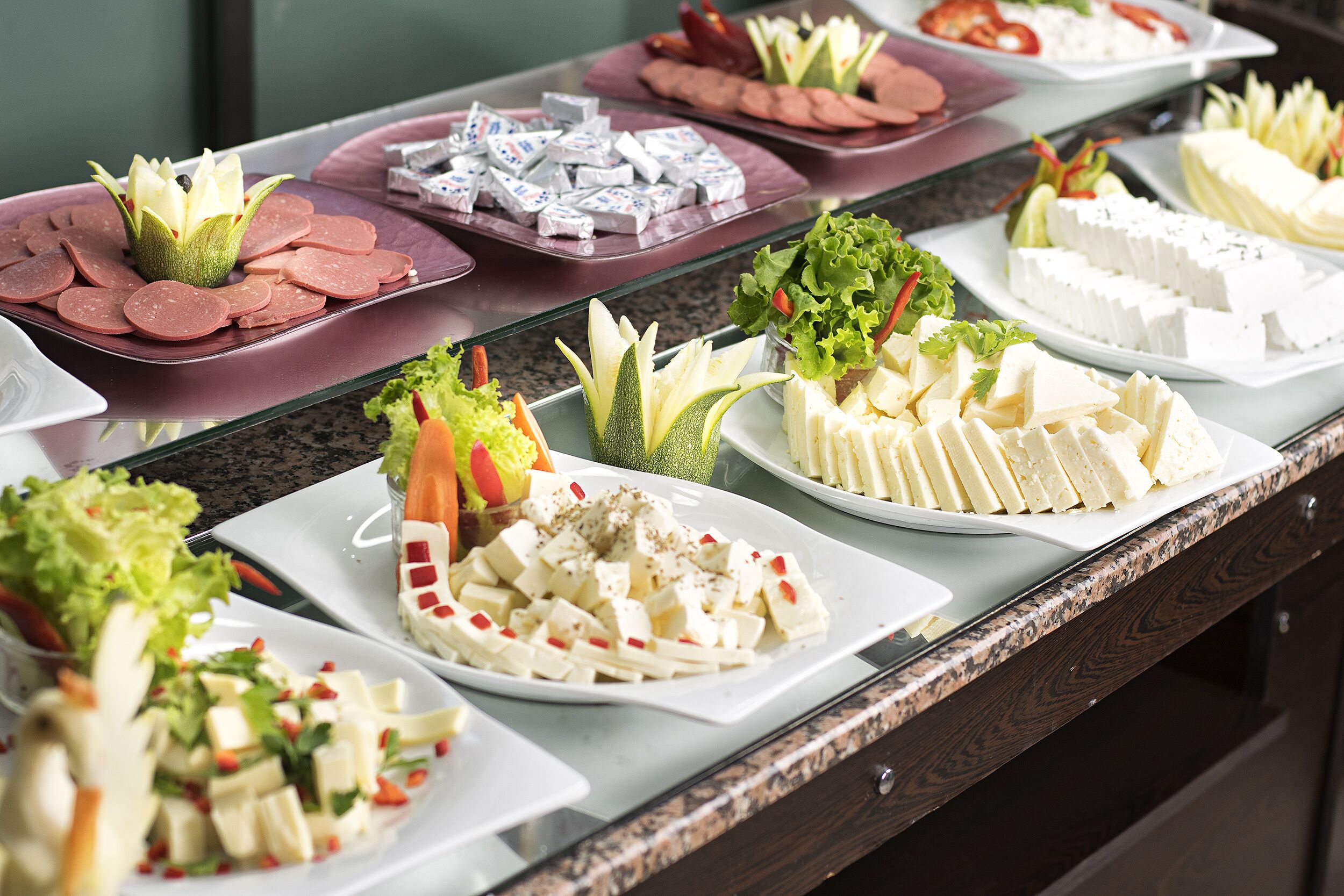 A buffet with various food items including sliced meats, cheeses, and salads.