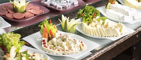 Un bufé con diversos alimentos, incluyendo fiambres, quesos y ensaladas.
