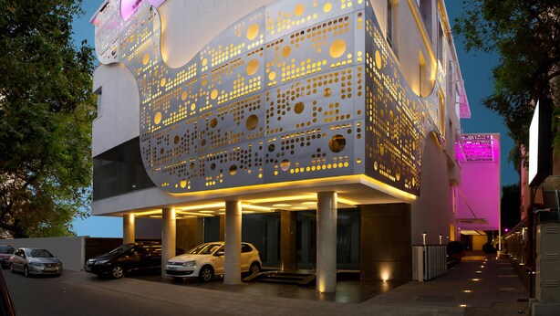 Un bâtiment moderne doté d’une façade perforée originale et d’une enseigne lumineuse indiquant « URVASHI RESIDENCY ».