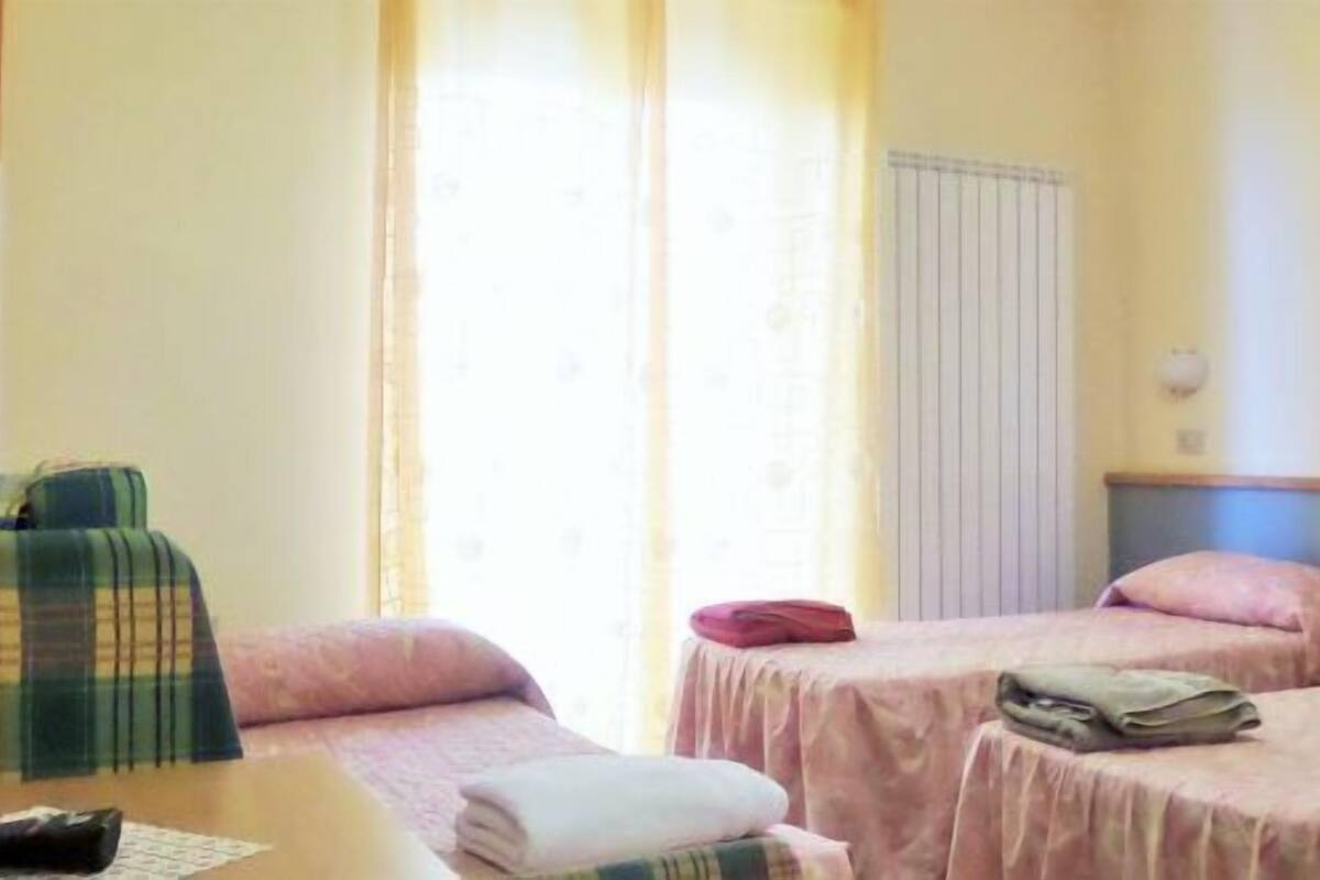 A hotel room with two beds, a table, and a plaid bag.