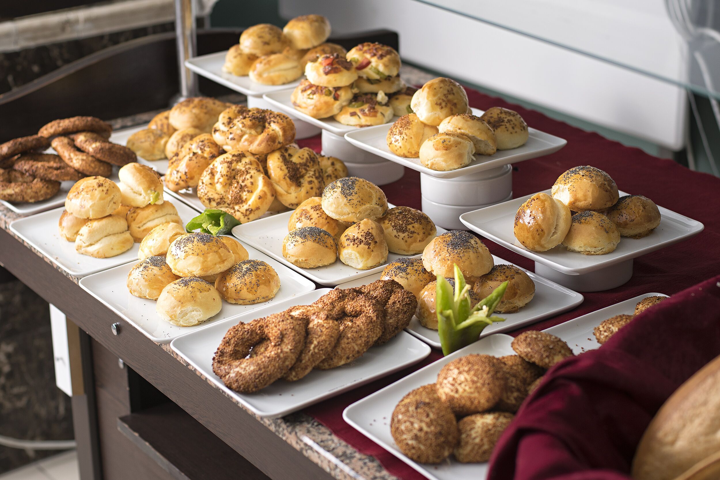 A buffet table with various baked goods including bread rolls, croissants, and pastries.