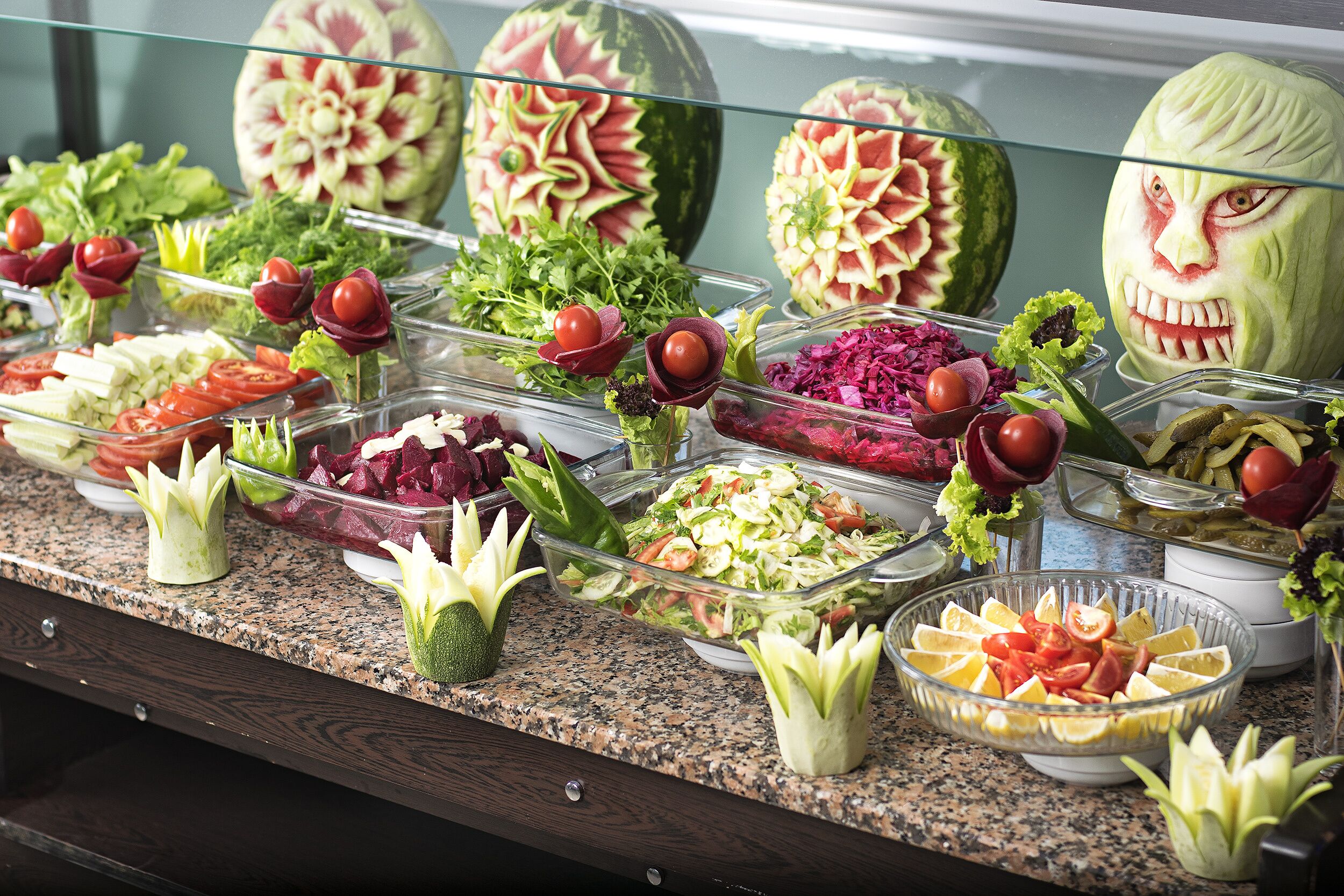 Un buffet proposant une variété de plats, notamment des salades, des fruits et des légumes, disposés sur un comptoir en granit.