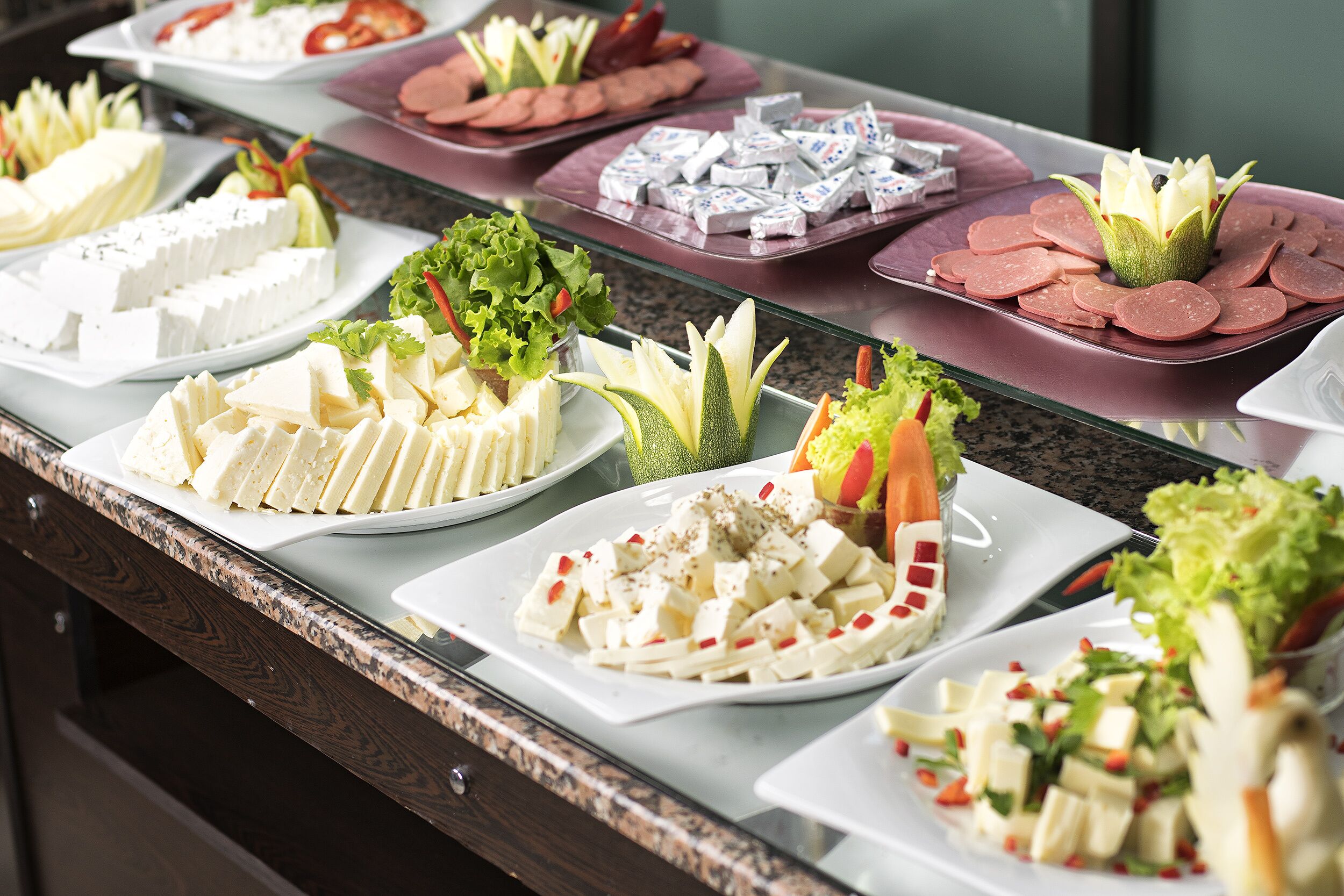 A buffet with various food items including cheese, salads, and meat.