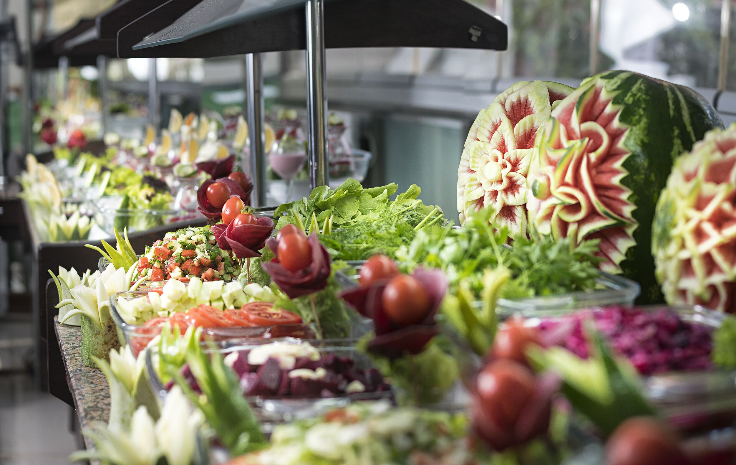 A buffet with various food items and a watermelon with intricate carvings.