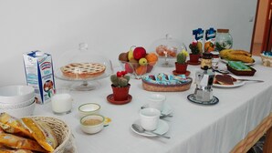 Una mesa de buffet con diferentes alimentos, como frutas, pasteles y bebidas.