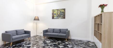A room with two grey sofas, a wooden cabinet, and a painting on the wall.