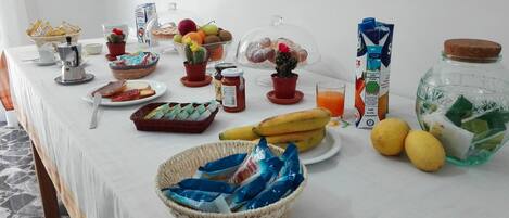 A breakfast buffet with various food items, including fruits, pastries, and beverages.
