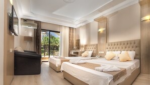 Une chambre d’hôtel avec deux lits, un canapé, un bureau et une grande fenêtre donnant sur des palmiers.
