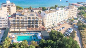 Un hôtel situé sur la côte, composé de plusieurs bâtiments, doté d’une piscine et offrant une vue sur la mer.