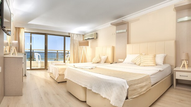 Une chambre spacieuse avec un grand lit, un bureau et une vue sur la mer.