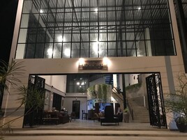 Un edificio moderno con fachada de vidrio, una escalera y una zona de recepción con asientos.