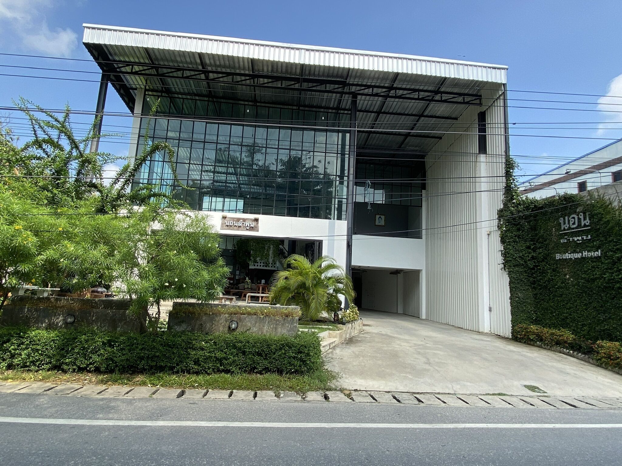 A modern building with a glass facade, a covered entrance, and a sign for a boutique hotel.