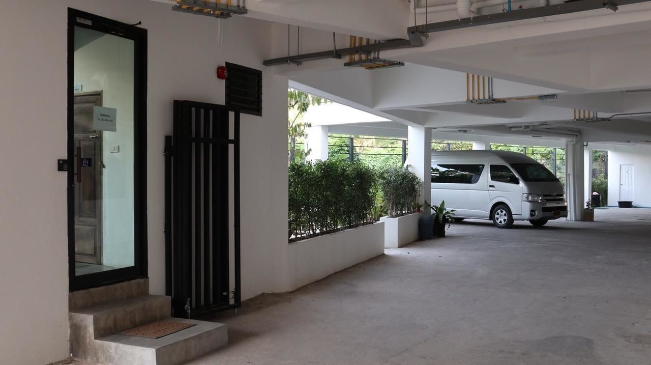 A parking garage with a white van parked inside, a door with a sign, and a small outdoor area with plants.