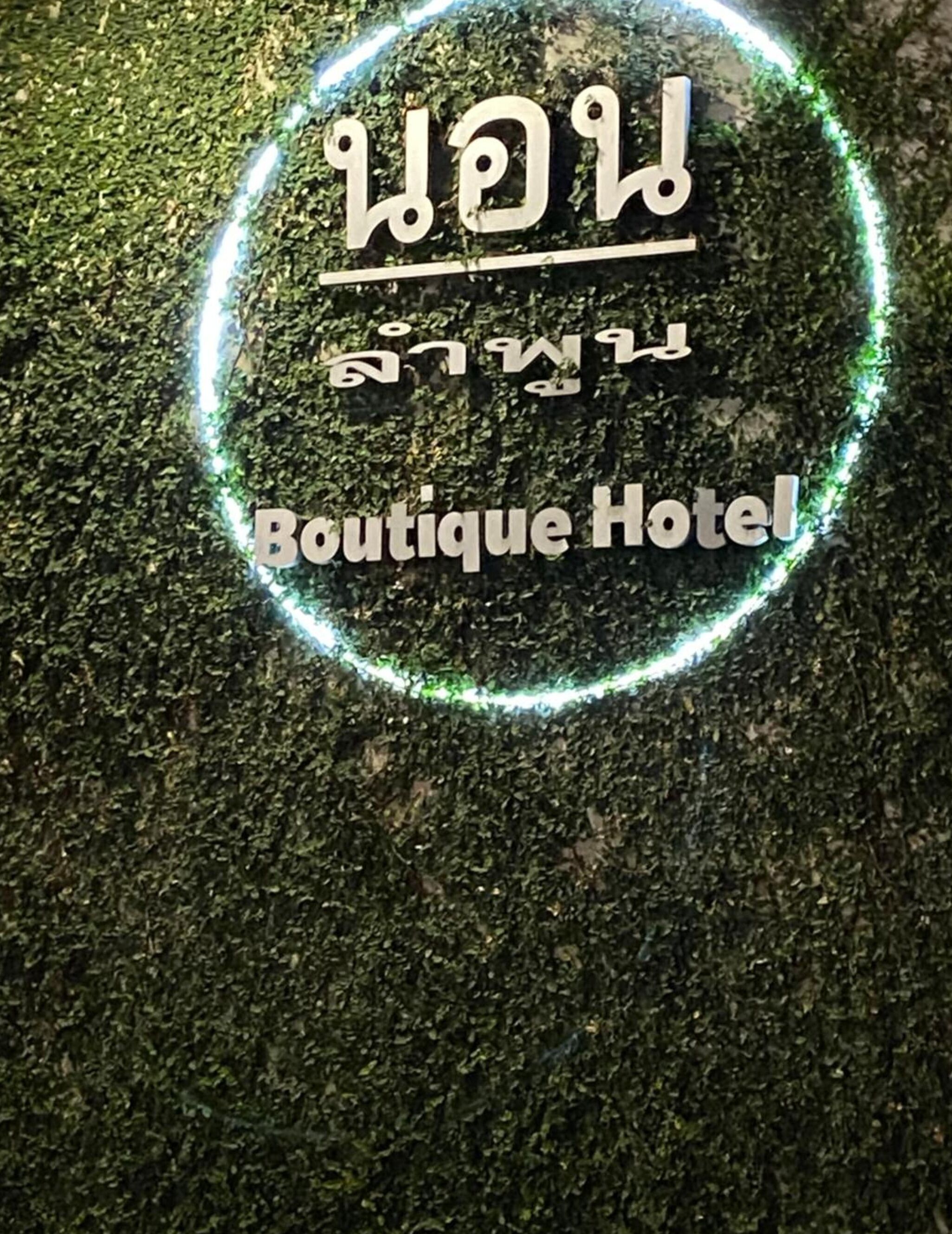 A circular sign with text in a non-Latin script and "Boutique Hotel" in English, surrounded by a green light outline.
