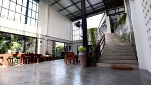 Amplio espacio interior con una escalera, muebles de madera y plantas en macetas.