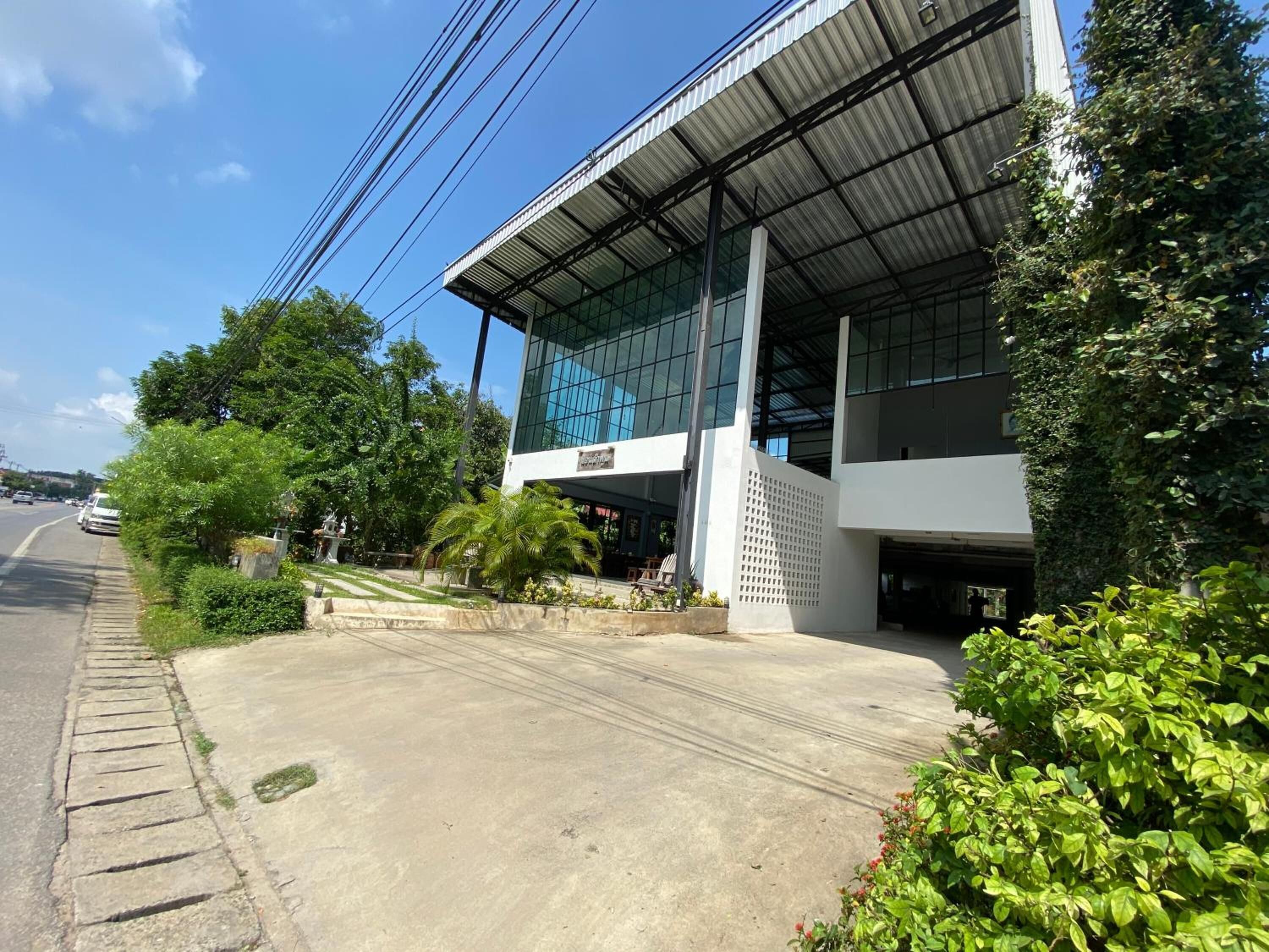 A modern building with a glass facade, a covered entrance, and a paved sidewalk.