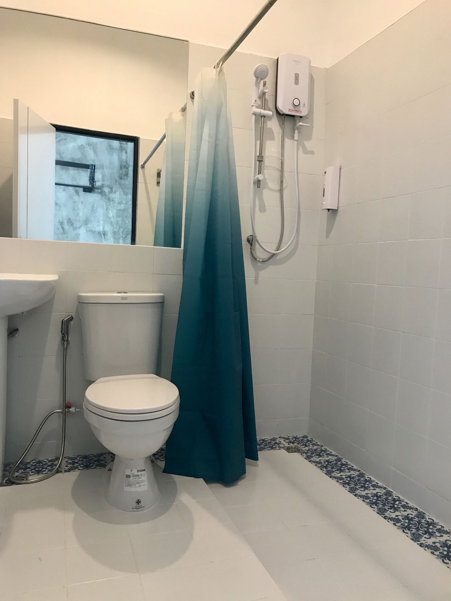 A bathroom with a toilet, a shower with a curtain, a sink, and a mirror.