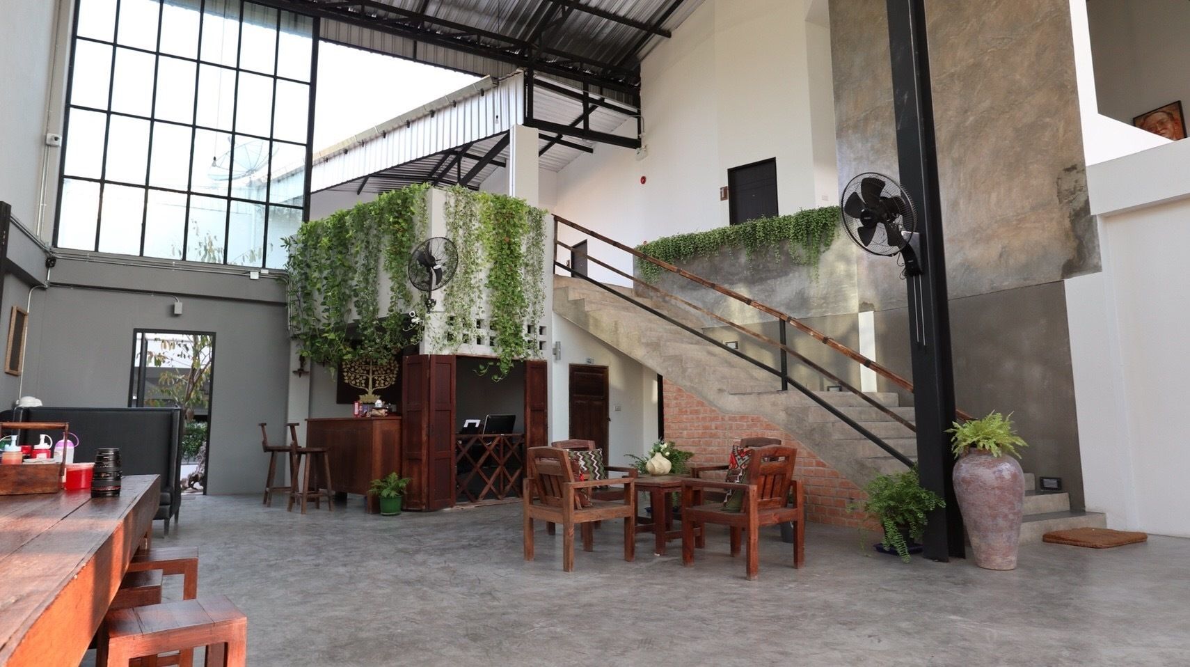 A spacious indoor area with a staircase, wooden furniture, and a large window.