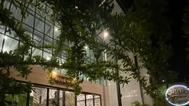 Un edificio moderno con fachada de vidrio, área de estar al aire libre y plantas en macetas.