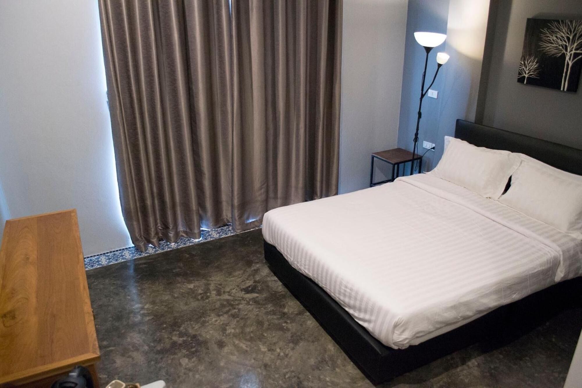 A hotel room with a bed, a desk, a lamp, and a painting on the wall.