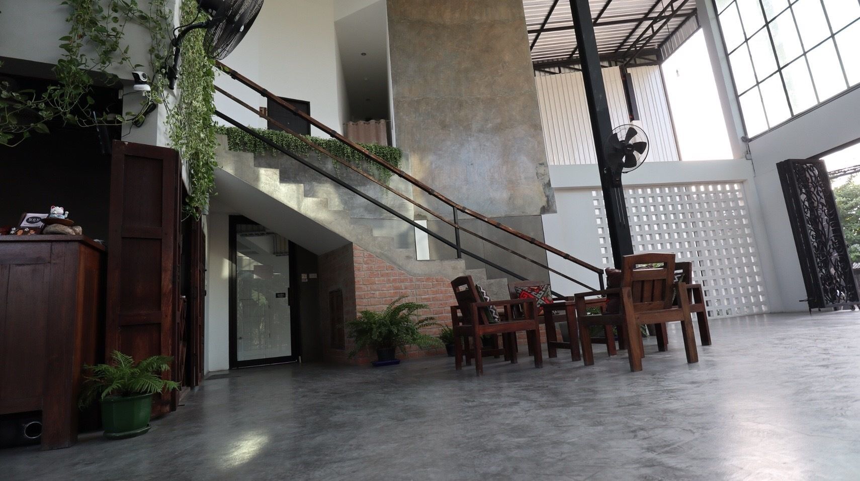 A spacious indoor area with a staircase, wooden furniture, and potted plants.